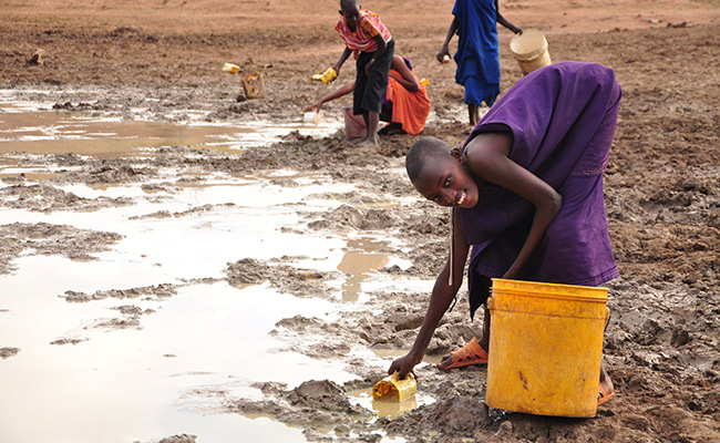 Girl collects watering from a muddy water hole in Kenya