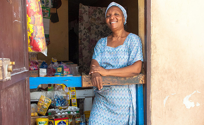 Yvette stands proudly at the door of her grocery store set up with support from