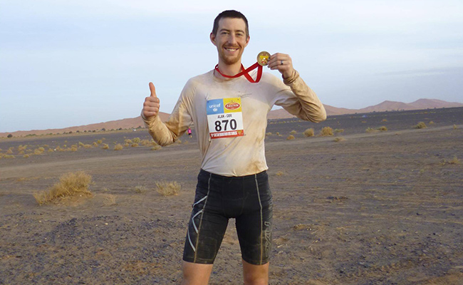 Alan Wood, long distance runner, holding his medal finishing Sahara desert run