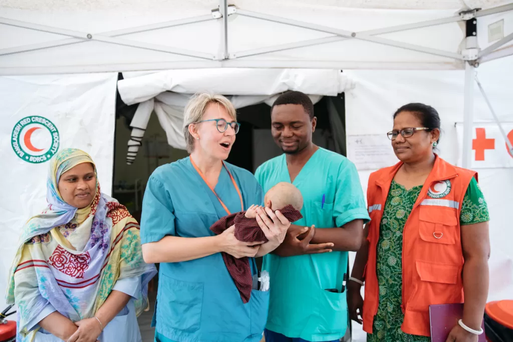 Doctors and nurses hold a baby outside a field hospital